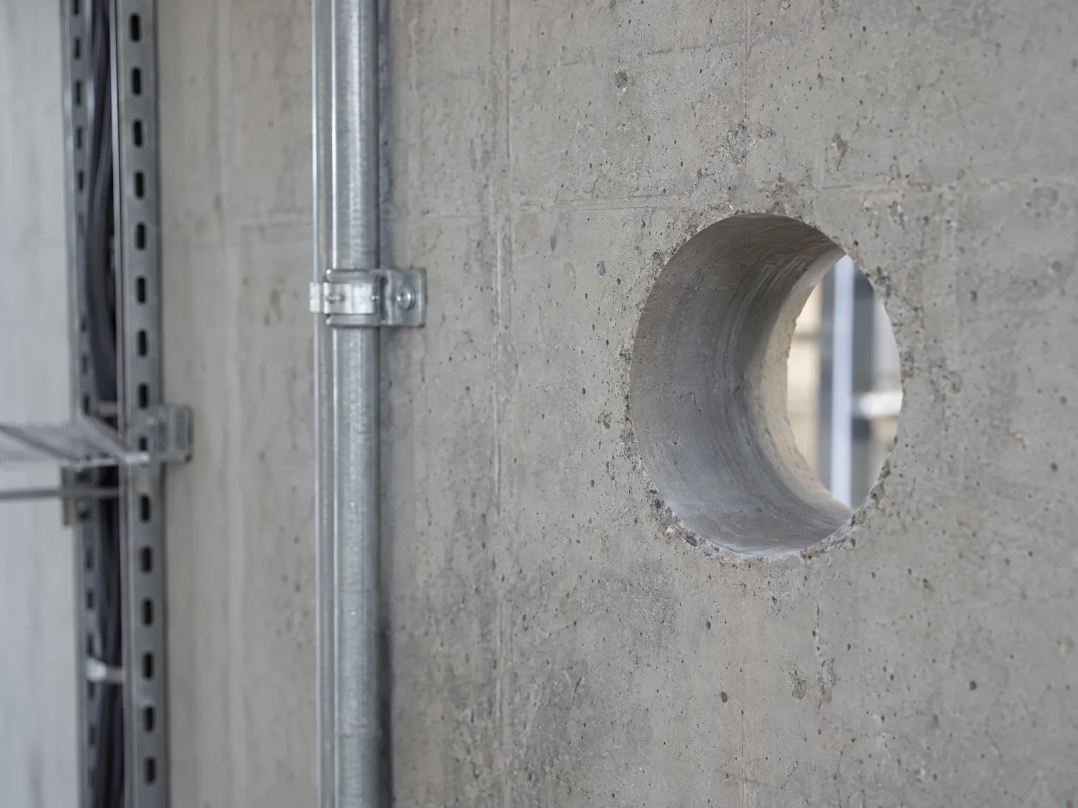 Metallische Kabeltrasse mit Kernbohrung in Betonwand montiert
