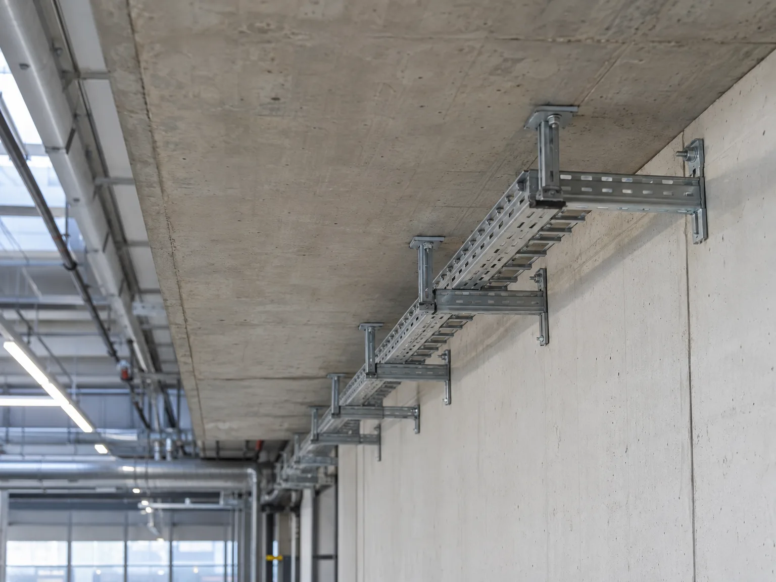 Gitterrinnen-Montage in Industriehalle an Betonwand mit Stahlkonsolen installiert