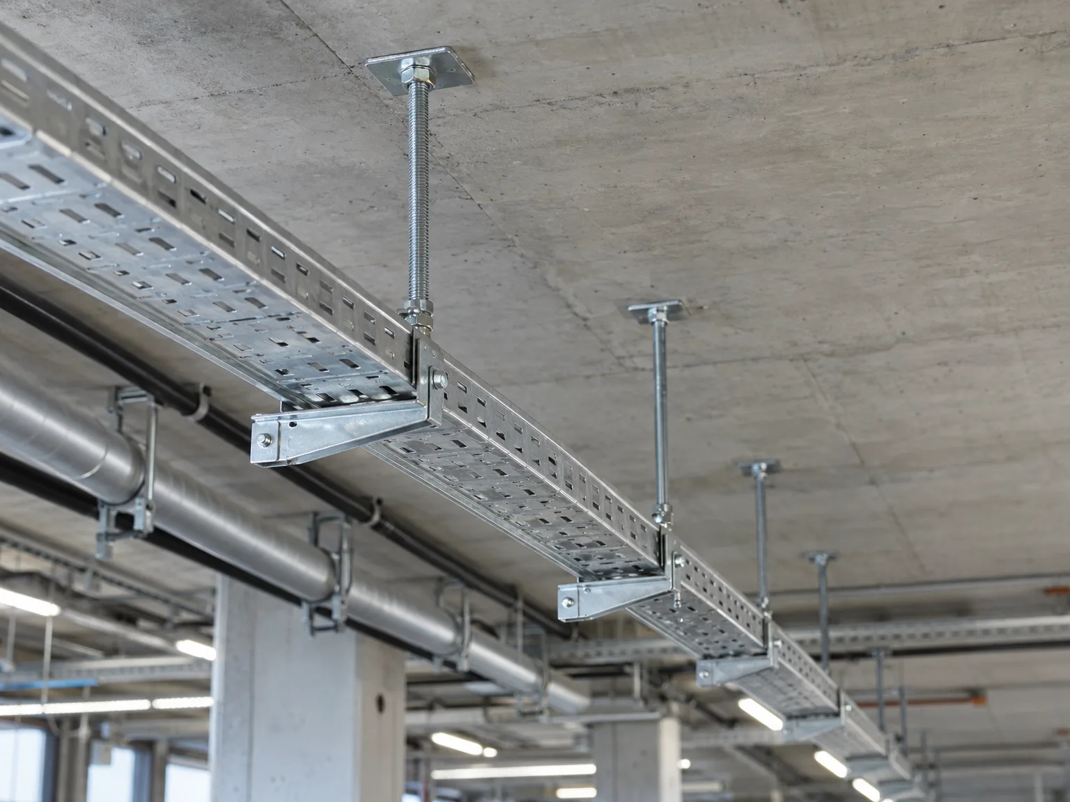 Gitterrinne mit Ankerbolzen an Betondecke in Industriehalle montiert