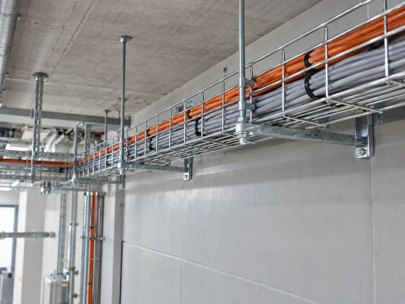 Kabeltragsystem mit Gitterrinnen und Kabelverlegung in Industriehalle, verzinkte Stahlkonstruktion, professionelle Montage