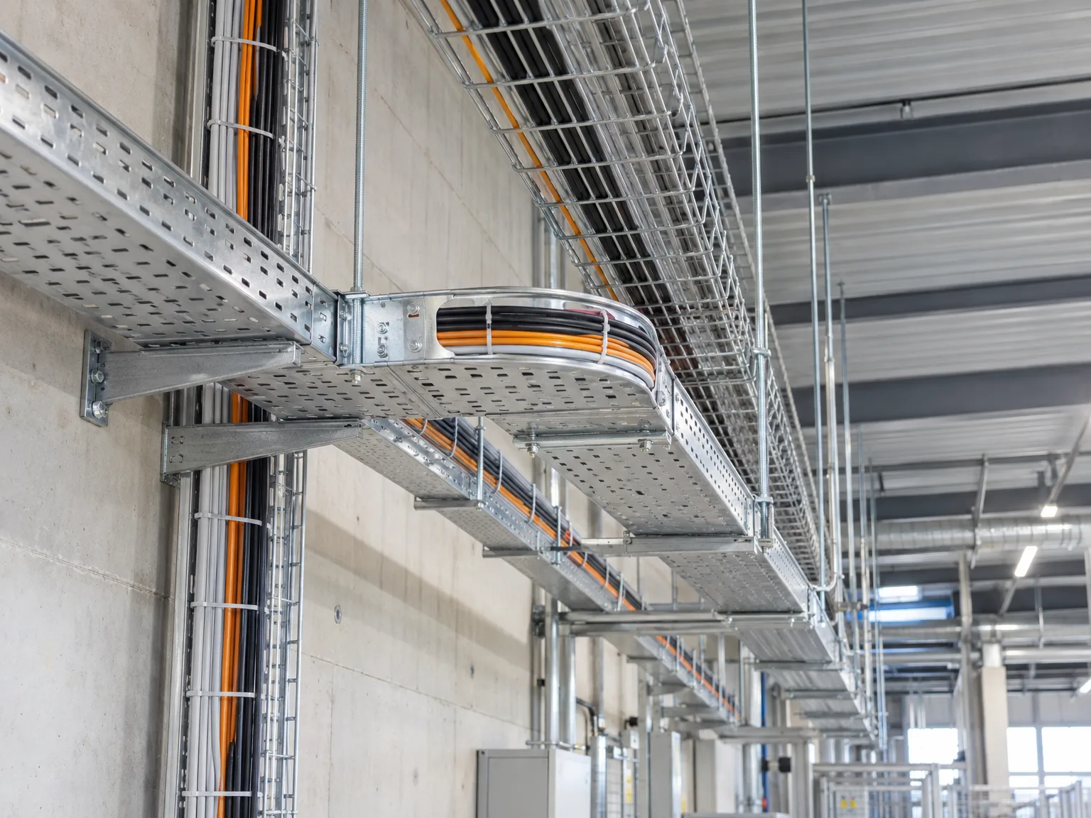 Kabelrinnen montiert mit orangen Stromkabeln in Industriehalle